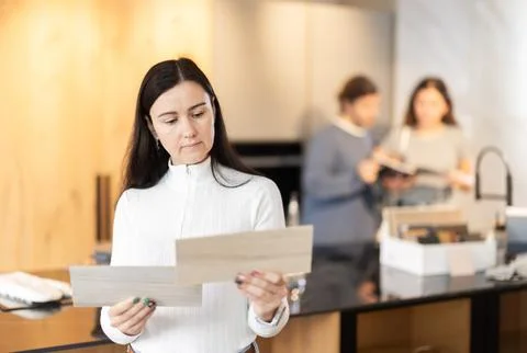 Female shopper carefully selects samples of material for a future kitchen set in Stock Photos