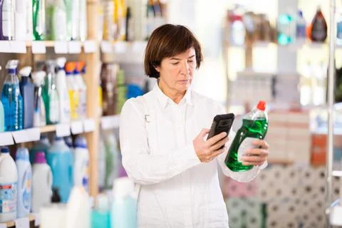 Female shopper checks a QR code on a dishwashing sponge label in supermarket Foto stock