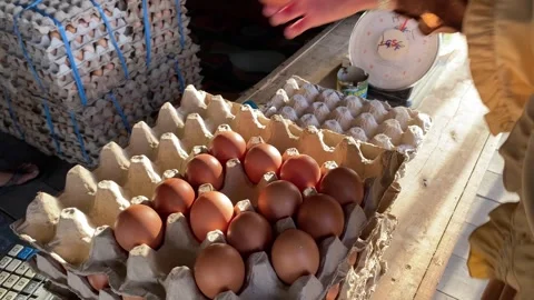 A female shopper chooses eggs to be weighed by a merchant. Stock Footage 278903606