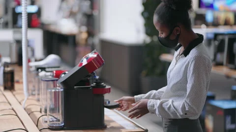 Female shopper is choosing automatic coffee maker in home appliance store, afro Stock Footage 153076122