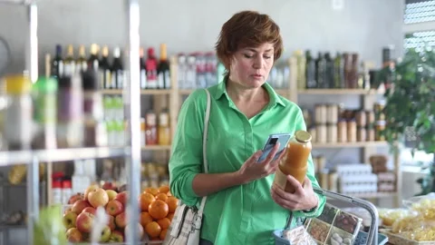 Female shopper scanning QR code on bottle peach juice label in grocery Stock Footage 306453173