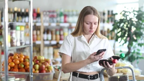 Female shopper scanning QR code on bottle soy sauce label in grocery department Stock Footage 306974966