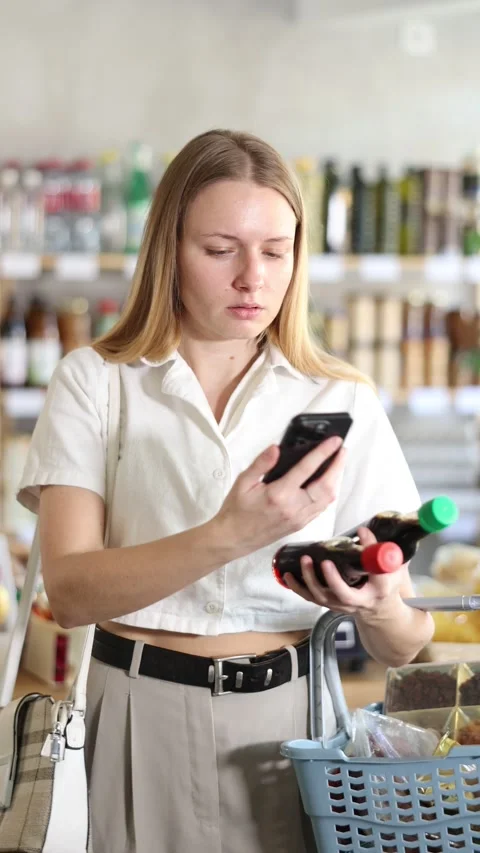 Female shopper scanning QR code on bottle soy sauce label in grocery department Stock Footage 310277571