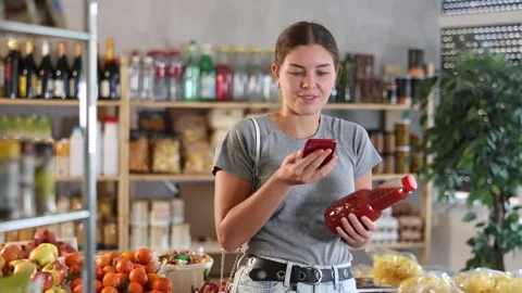 Female shopper scanning QR code on bottle tomato juice label in grocery Stock Footage 310685545