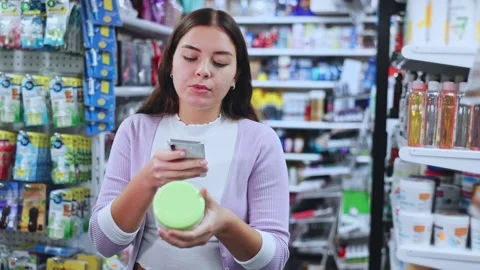 Female shopper scanning a QR code using a mobile phone in a cosmetics store Stock Footage 316574963