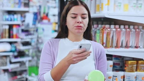 Female shopper scanning a QR code using a mobile phone in a cosmetics store Stock Footage 327694421