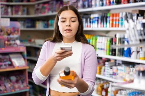 Female shopper scanning a QR code using a mobile phone in cosmetics store Stock Photos