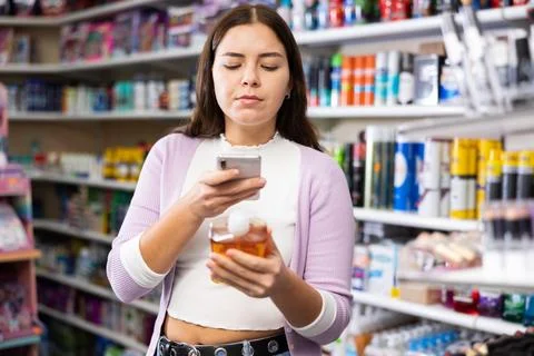 Female shopper scanning a QR code using a mobile phone in cosmetics store Stock Photos