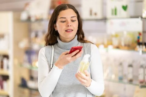 Female shopper scanning QR code on perfume in perfume shop Photos
