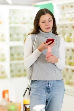 Female shopper scanning QR code on perfume in perfume shop Photos
