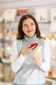 Female shopper scanning QR code on perfume in perfume shop Photos