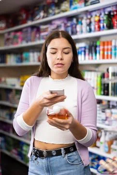 Female shopper scanning a QR code using a mobile phone in cosmetics store Stock Photos