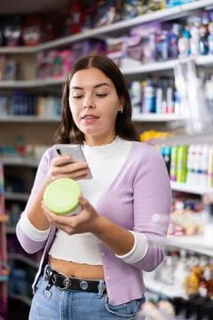 Female shopper scanning a QR code using a mobile phone in cosmetics store Foto stock