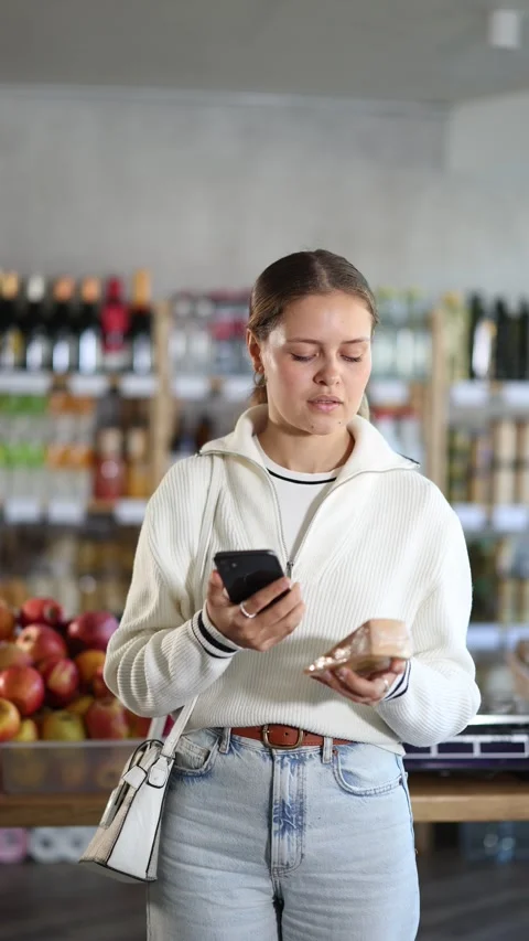 Female shopper scans the barcode on a cheese package. Grocery store visitor uses Stock Footage 325031910