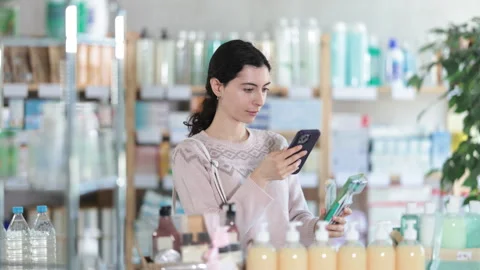 Female shopper scans code on toothbrush label to check the expiration date Stock Footage 312632437