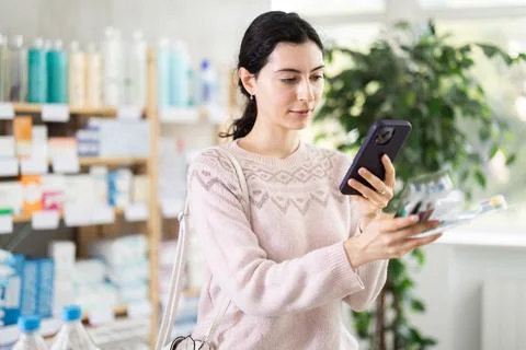 Female shopper scans code on toothbrush label to check expiration date Fotos de archivo