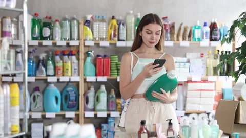 Female shopper scans QR code on label of shampoo or shower gel using her Stock Footage 332737047