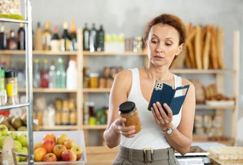 Female shopper scans QR code on lentils label using smartphone. Checking Foto stock