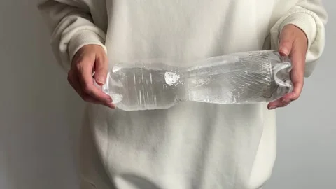 Female showing a half empty plastic bottle for recycling and eco awareness Video stock 336966730