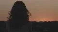 Female silhouette enjoying view of pink sky at sunset, holding scarf in the wind 4k or 4k+ Resolution
