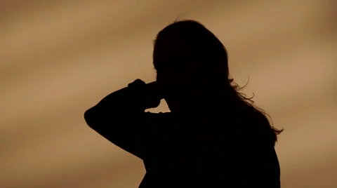 Female silhouette goes with her hands through her hair Stock Footage