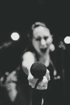 Female singer performs into microphone during dark band sound check Stock Photos