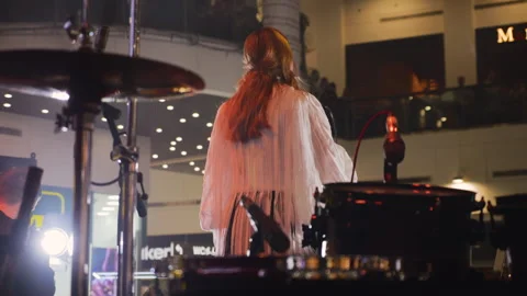 A female singer performs on a stage in a modern shopping mall atrium.  Stock Footage 329144650