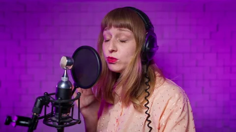 Female singer in recording studio performs song into microphone with pop filter Stock Footage 164317171