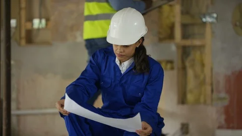 Female site worker reading plan and smiling at camera at site Stock Footage 108175330