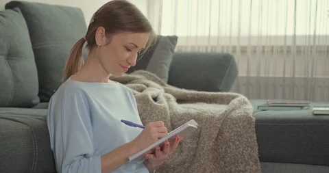 Female sitting on the carpet, leaned on the sofa at the day in her apartment Stock Footage 124508544