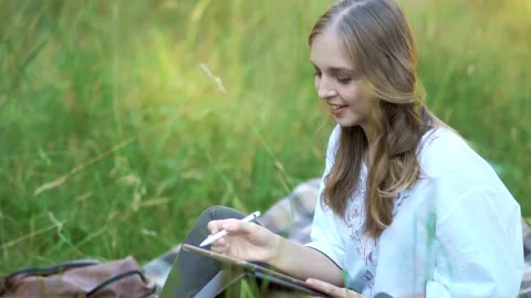 Female sketching digitally while seated outside Stock Footage 231258512