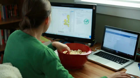 Female snacking on popcorn while working in a home office Stock Footage 33344226