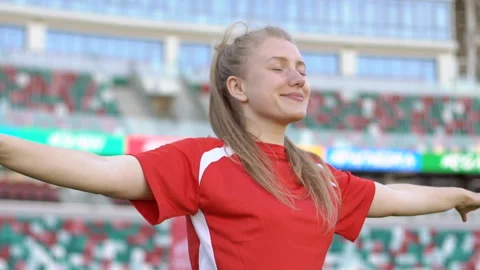 Female soccer player with raised hands and closed eyes standing at the stadium Stock Footage