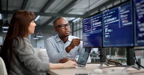 Female Software Developer Codes On Computer While A Manager Leads Training Stock Photos