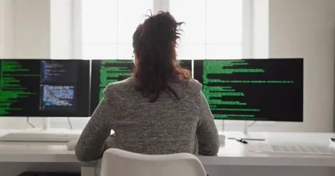 Female software developer coding at multi monitor workstation in modern office Stock Footage 331127164