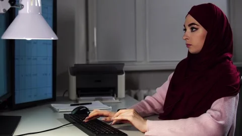 Female software developer in hijab demonstrating focus during coding in modern 库存影片 343902919