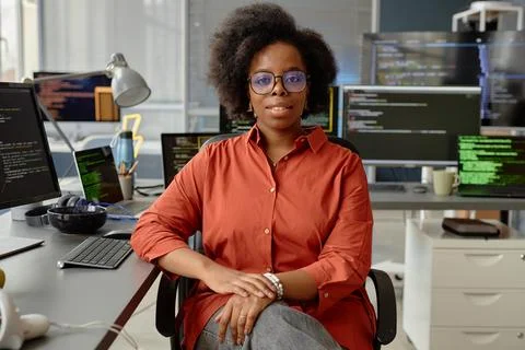 Female Software Developer in Orange Shirt at Desk 写真素材