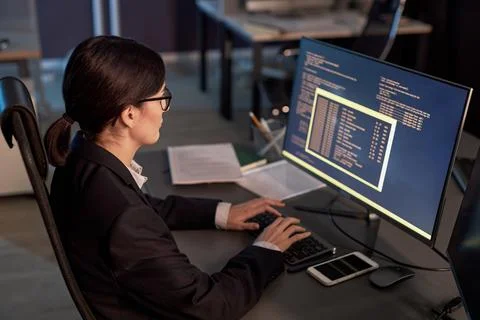 Female software developer writing code while using computer at workplace Stock Photos