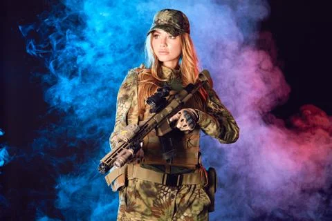 Female soldier in military camouflage uniform and cap holding sniper rifle Stock Photos
