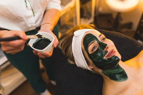 Female SPA client with half of face covered in black mask. Beauty and skincare Stock Photos