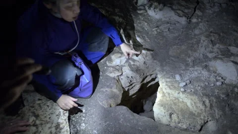 Female speleologist exploring a dark cave with flashlight Stock Footage 330553261