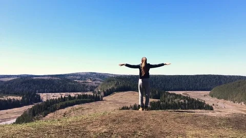 Female spread her arms out to the sides when climbed to the top of mountain Stock Footage 75950853