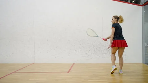 Female squash player hits ball with racket against wall Stock Footage 228739999