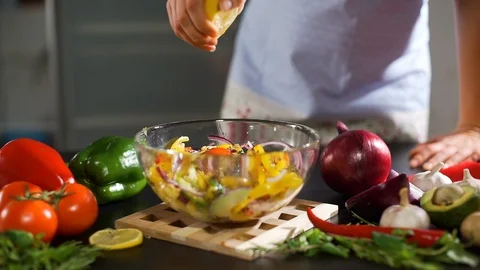 Female Squeezing Lemon Juice into Bowl with Salad Stock Footage 125976341