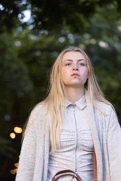 Female standing in garden under string lights, wearing zip-front blouse, Stock Photos