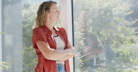 Female standing by glass panel, noticing camera reflection, turning toward Stock Footage 342597041