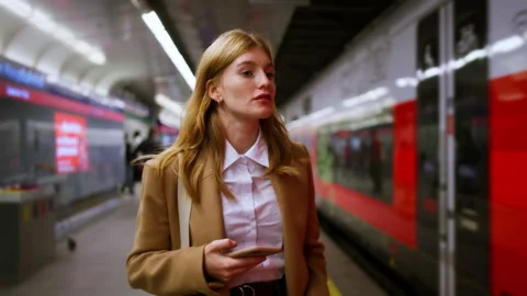 Female standing at subway platform with mobile phone, using social media and Stock Footage 264262743