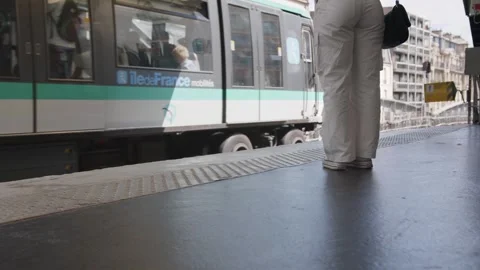 Female standing on train platform waiting as Paris Metro arrives at station Stock Footage 254711905