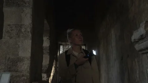 Female stands with a lantern in a dark corridor inside the amphitheater Stock Footage 225069741