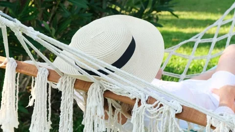 Female in a straw hat is resting in a hammock around the palm trees and enjoying Stock Footage 169593744
